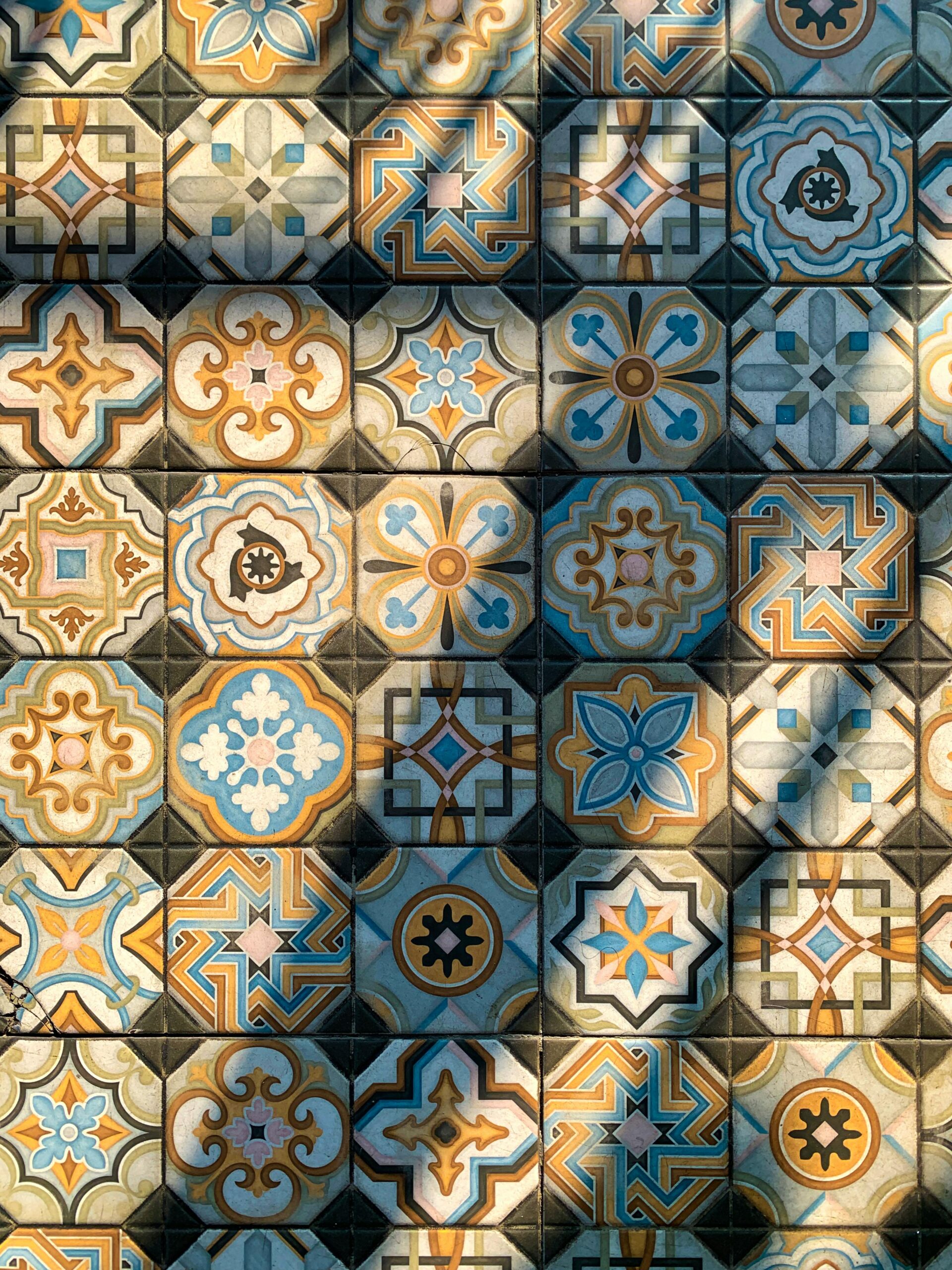 Colorful patterned ceramic tiles with geometric and floral designs in blue, yellow, and beige tones.
